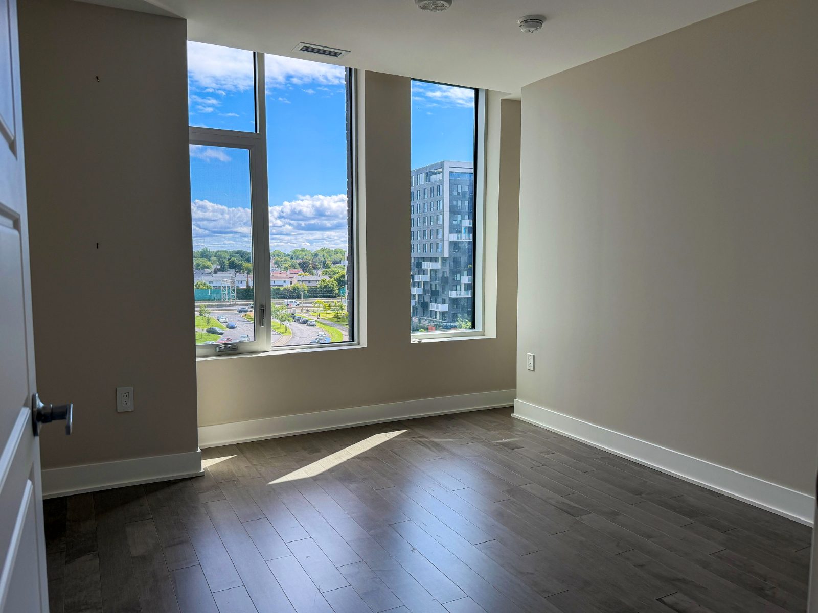 Bright second bedroom with large windows and wood floors