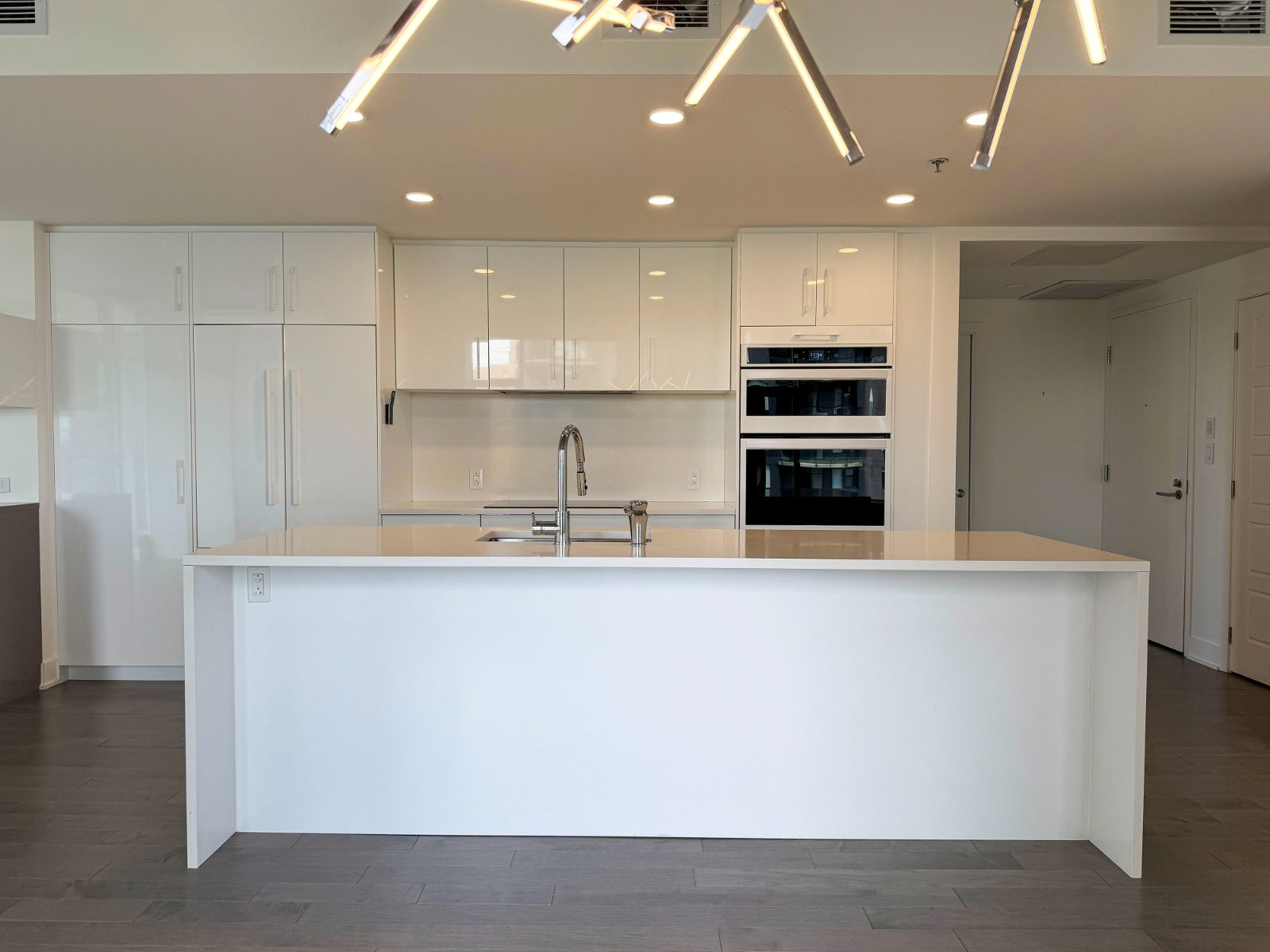 Cuisine blanche de designer avec vaste îlot en quartz et électroménagers encastrés