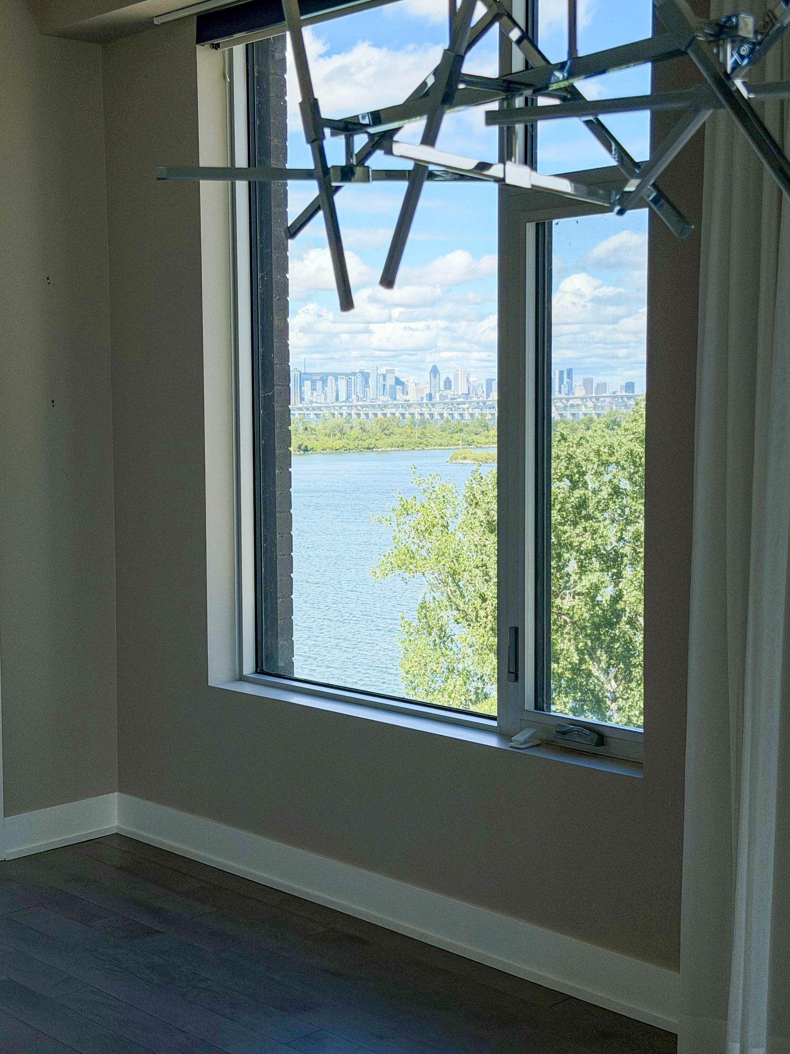 Fenêtre du séjour ouverte sur le fleuve Saint-Laurent et le centre-ville de Montréal